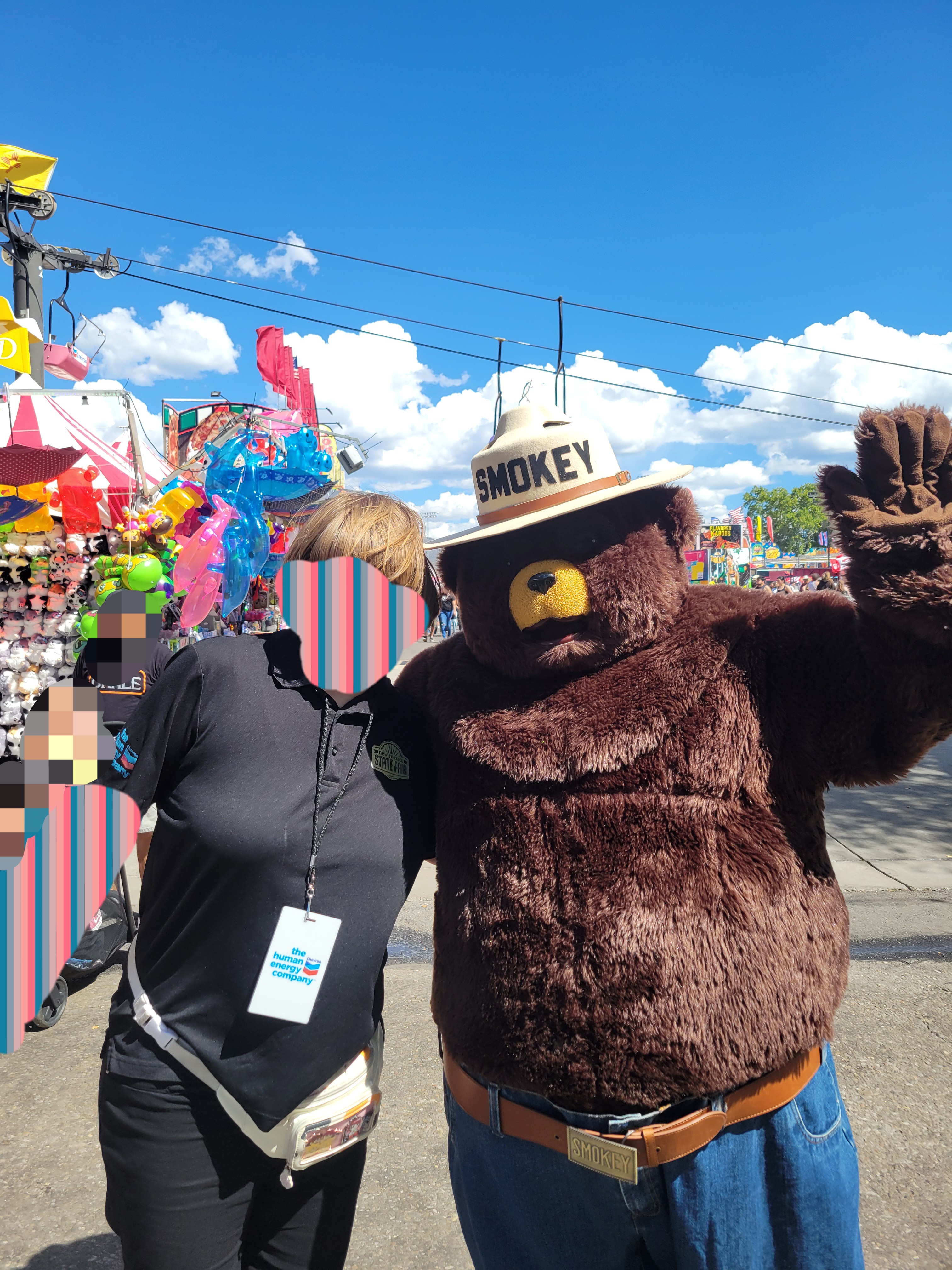 State fair worker poses with Smokey bear mascot for a photo.